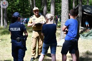 Zdjęcie kolorowe. Policjantka i strażak rozmawia z organizatorami