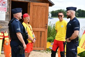 Zdjęcie kolorowe. Policjanci rozmawiają z ratownikami