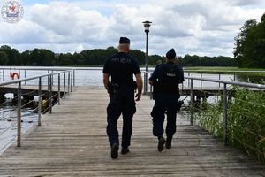 Zdjęcie kolorowe. Policjanci obserwują plaże  jeziora Trzesiecko