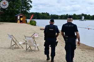 Zdjęcie kolorowe. Policjanci obserwują plaże  jeziora Trzesiecko