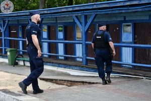 Zdjęcie kolorowe. Policjanci obserwują plaże  jeziora Trzesiecko