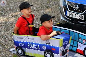 Zdjęcia kolorowe. Dzieci siedzą w małych edukacyjnych samochodzikach