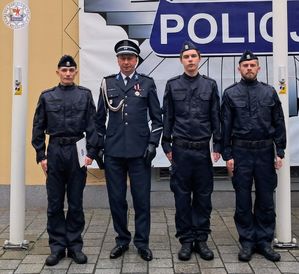 Zdjęcie kolorowe. Komendant stoi w szeregu z nowymi funkcjonariuszami