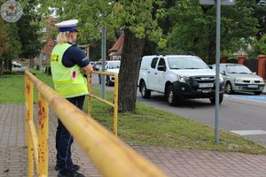 Zdjęcie kolorowe. Policjantka ruchu drogowego stoi w pobliżu śluzy przy przejściu dla pieszych