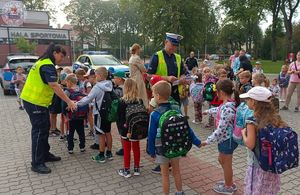 Zdjęcie kolorowe. Policjanci wręczają elementy odblaskowe