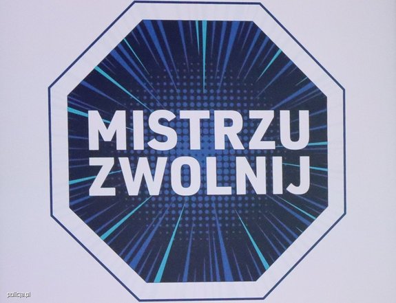 Zdjęcie kolorowe. W ośmiokąt wpisany napis Mistrzu zwolnij