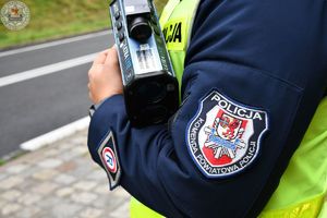 Zdjęcie kolorowe. Policjant trzyma miernik prędkości