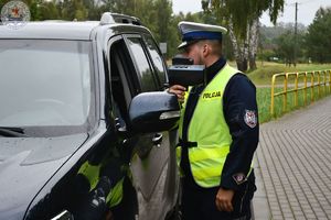 Zdjęcie kolorowe. Policjant rozmawia z kierującym zatrzymanym do kontroli