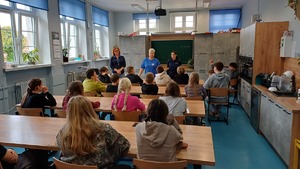 Zdjęcie kolorowe. Policjantka na spotkaniu w szkole z uczniami