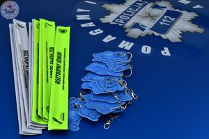 Zdjęcie kolorowe. Policjanci ruchu drogowego rozdają odblaski przechodniom