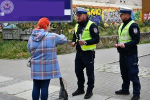 Zdjęcie kolorowe. Policjanci ruchu drogowego rozdają odblaski przechodniom