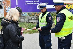 Zdjęcie kolorowe. Policjanci ruchu drogowego rozdają odblaski przechodniom