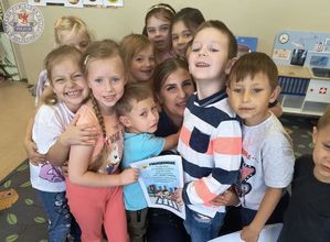 Zdjęcie kolorowe. Przedszkolacy tulą się do policjantki