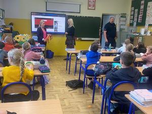 Zdjęcie kolorowe. Dzielnicowy na spotkaniu z uczniami.