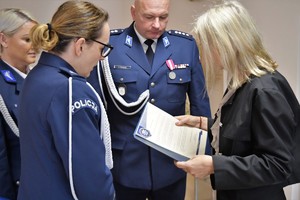 Zdjęcie. Pani dyrektor czyta lis u jej boku stoi komendant i naczelnik
