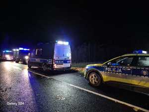 Zdjęcia kolorowe. Zdjęcia zrobione nocą. Na jednym pasie ruchu stoją zaparkowane pojazdy służb.