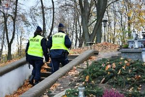 Zdjęcie kolorowe. Policjanci patrolują cmentarz