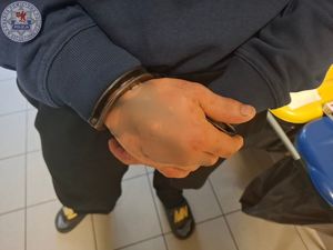 Zdjęcie kolorowe. Kajdanki założone na rękach zatrzymanego