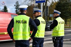 Zdjęcie kolorowe. Policjanci ruchu drogowego pełniący służbę w obrębie cmentarza