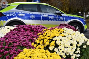 Zdjęcie kolorowe. Policjanci ruchu drogowego pełniący służbę w obrębie cmentarza