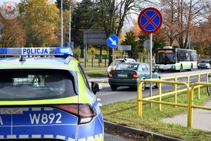 Zdjęcie kolorowe. Policjanci ruchu drogowego pełniący służbę w obrębie cmentarza
