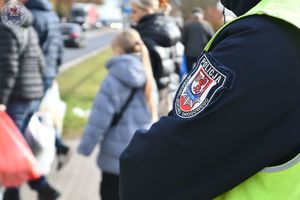 Zdjęcie kolorowe. Policjanci ruchu drogowego pełniący służbę w obrębie cmentarza