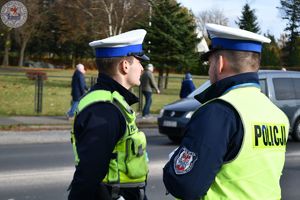 Zdjęcie kolorowe. Policjanci ruchu drogowego pełniący służbę w obrębie cmentarza