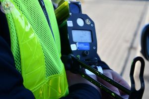 Zdjęcie kolorowe. Policjant ruchu drogowego podczas działań prędkość