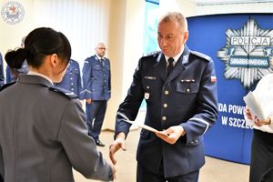 Zdjęcie kolorowe. Komendant wręcza akt mianowani policjantce