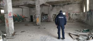 Zdjęcie kolorowe. Policjant kontroluje pustostan