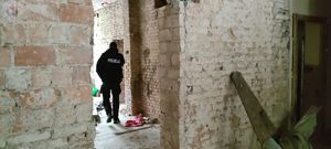 Zdjęcie kolorowe. Policjant kontroluje pustostan