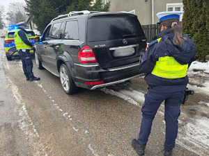 Zdjęcie kolorowe. Kontrola pojazdu przez policjanta ruchu drogowego