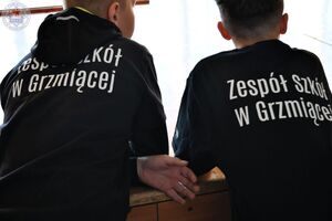Zdjęcie. Dwóch chłopców odwróconych plecami z białym napisem  na plecach ZS w Grzmiącej