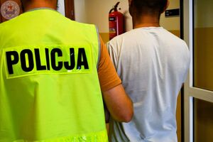 Zdjęcie kolorowe. Policjanci prowadzą osobę zatrzymaną