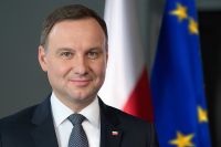 Zdjęcie kolorowe. Na zdjęciu Prezydent RP Andrzej Duda na tle flagi Polski i UE