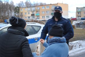 Dzielnicowy wręcza dwóm kobietą torbę z napisem POLICJA